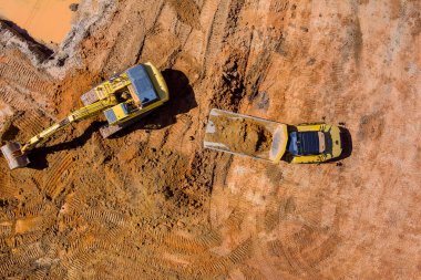 İnşaat alanındaki çöp kamyonlarına yüklemek için toprağı boşaltan kazıcıyla hazırlık çalışması