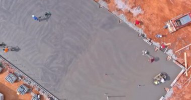 İnşaat alanındaki temel zemine dökülen çimentoyu parlatmak için işçiler tarafından beton cilalama makineleri kullanılıyor.