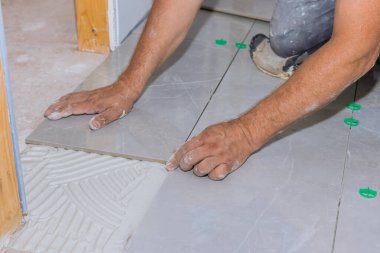 Tile levelling system with plastic clips and wedges in bathroom construction working