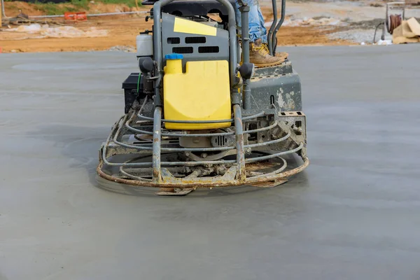 Concrete polishing machines are being used by workers to polish the cement after it has been poured on the foundation floor in construction site