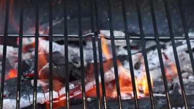 Cooking barbecue over laming ot harcoal on a metal barbecue grill