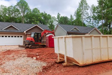 İnşaat alanındaki binanın altında bir endüstriyel çöp konteynırı var.