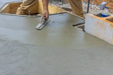 Çelik mala tutan Mason işçisi inşaat alanındaki beton zemine alçı döşeme ile yumuşatılıyor.