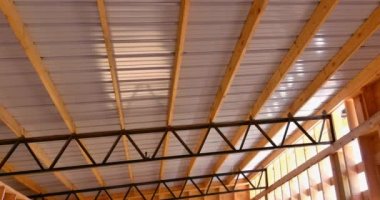 Roofing metal panels cover the roof of a metal frame warehouse in construction site