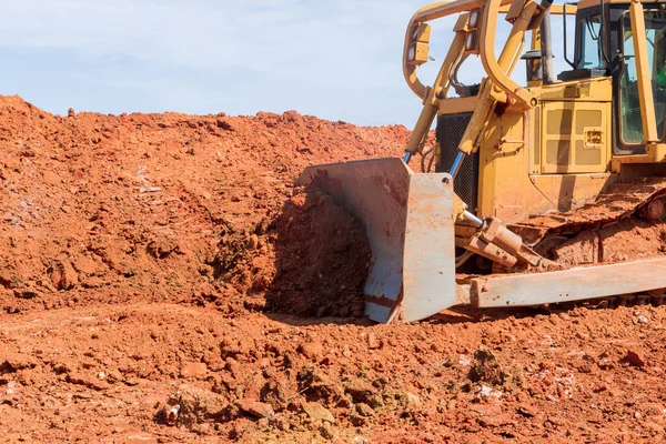 A bulldozer is working with moving earth soil while doing landscaping on construction site