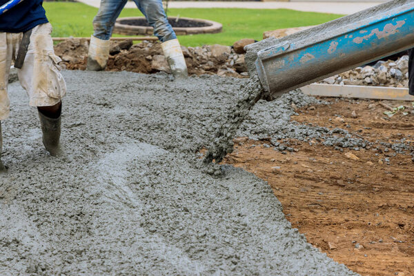 Paving a driveway on construction site while pouring wet concrete at new home