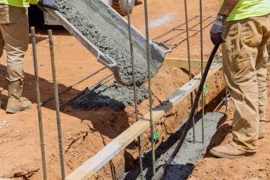 Concrete trenches are poured to form the foundation for house as a method of constructing solid wall in construction site