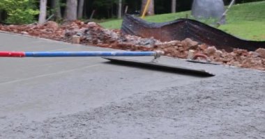 An contractor holds a steel fresno concrete trowel and smooths plaster on the freshly poured concrete in construction zone