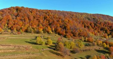 This a panoramic view of a mountain landscape in autumn while it is surrounded by forest near village
