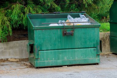 Located near an apartment building, there is a container bin for garbage