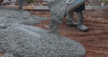 Pouring wet concrete while paving a driveway at construction site near new home