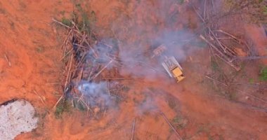 New plot land development for new construction using heavy bulldozing equipment, uprooted and burning the woods an environmental problem