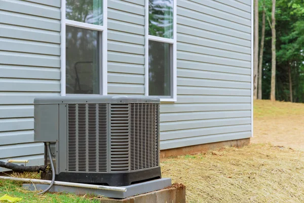 In vicinity of new house, an electric air conditioner is being installed outside for residential use