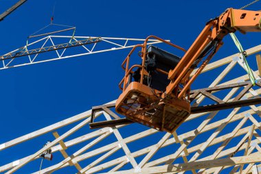 A worker nails beams the rafters a homes roof with an air hammer in construction of household
