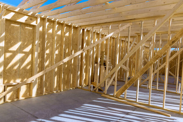 There are beams of wood stick framing in the construction site a new house