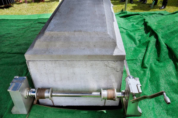 During a funeral service at cemetery, the coffin is placed on an automatic elevator before being lowered into the grave
