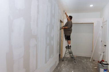 El işçisi macunları alçıpan üzerine serpiştiriyor macunu macunla bitiriyor.