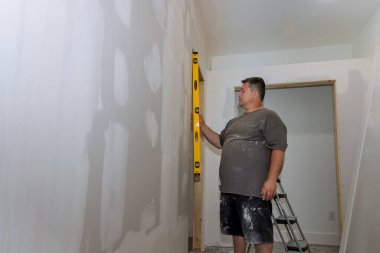 Duvarı boyamadan önce, bir çalışan duvarın seviyesini boyamadan önce kontrol eder.