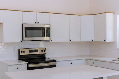 Yeni inşa edilen bir eve yeni mutfak aletleri ve beyaz mutfak dolapları yerleştiriliyor.