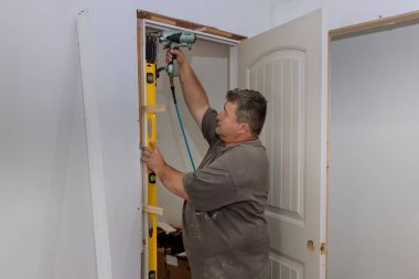 İç kapılar, marangozlu bir işçinin hava çivi tabancası kullanarak yeni bir eve monte ediliyor.