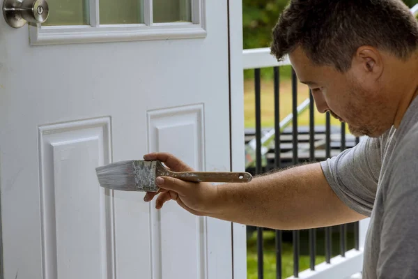 Worker painted wooden front door with paintbrush the renovation home