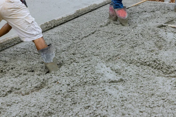During the pouring of concrete driveways, a worker is seen pouring concrete for parking car