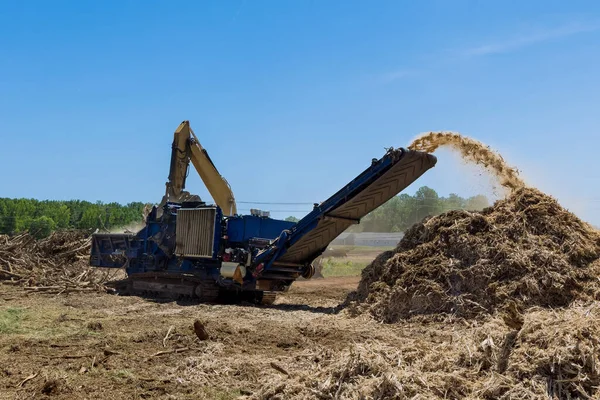 Land on which is going be built has roots that are being shred into chips by an industrial shredder machine to land clearing property housing development