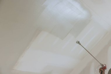 İşçilerin duvarları ve tavanları boyamak için astar ile sprey tabanca kullanmaları gerekiyor..