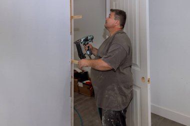 Yeni evin iç kapıları bir marangoz tarafından çivi tabancası kullanılarak döşeniyor.