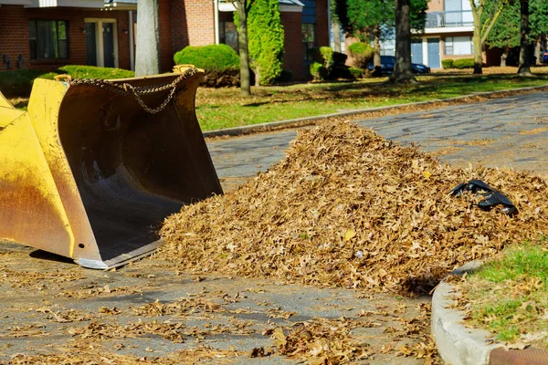 地元の労働者が家の周りから落ち葉をきれいにするためにブルドーザートラックを使用するのは秋には慣習的です — ストック写真