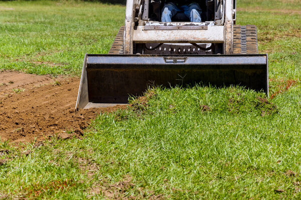 In landscaping work, bulldozer uses scoop to move earth in front of it
