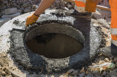 Foseptik tankı için çukur inşa eden bir elektrik işçisi var kanalizasyon kanalizasyonunu yeniden inşa eden bir rögar.