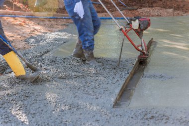 Tamping makinesi kullanılarak, sıkıştırılmış katman taze beton yeni garaj yolu inşaatında hizalanır.