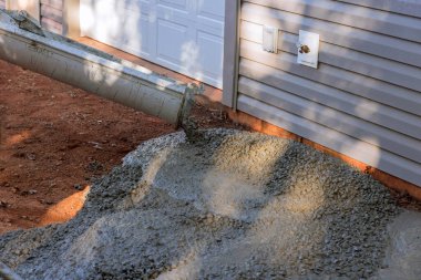 İnşaat sürecinde olan yeni evde, işçiler garaj yolunu dökerken ıslak beton döküyorlar..