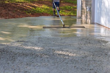 Mason işçisi beton döşeme döşemesini uzun mala kullanarak sıvadı.