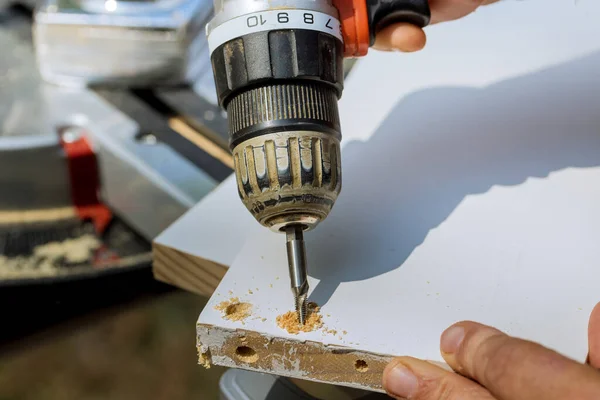 Carpenter drilling wood boards into using screwdriver for purpose of connecting them in construction process.