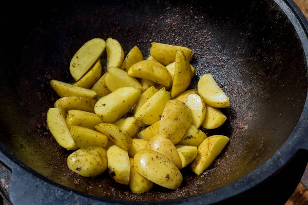 Potatoes frying in kazan cauldron on nature fire