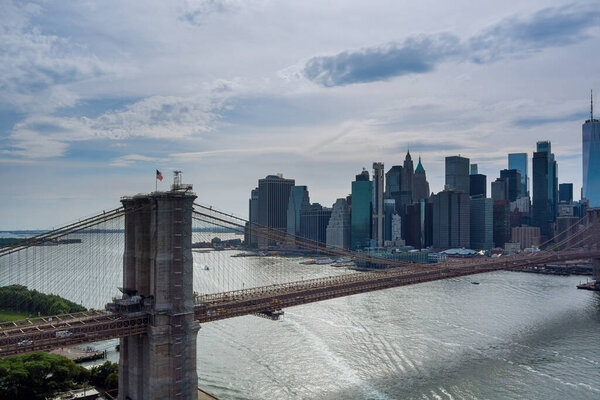 It is panoramic aerial view of Manhattan in the background along East River with picturesque Brooklyn Bridge