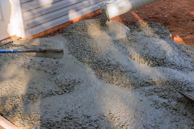 Yeni evin yakınındaki inşaat alanında, asfalt döşenirken garaj yoluna ıslak beton döküyoruz..