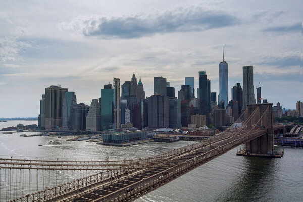 Manhattan in background along East River with picturesque Brooklyn Bridge New York City United States from panorama aerial view.