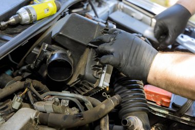 Tamirci el, servis merkezindeki araba motoruna hava filtresi takmak.