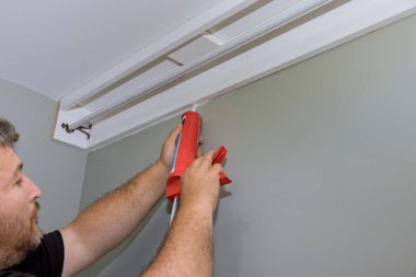 Cornice ve duvar arasındaki dikiş akrilik lateks caulk silikon dolgu ile doludur. İnşaat işçisi tarafından şırınga kullanılarak.