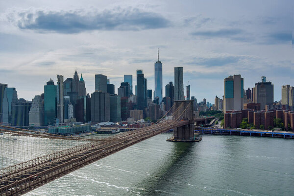 View Manhattan along East River over picturesque Brooklyn Bridge in New York City United States of America.