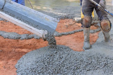 Beton müteahhit kaldırım yolu üzerinde çalışırken ıslak beton döker.