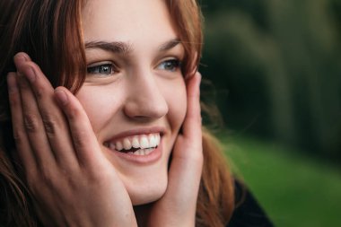 Şaşırmış, mutlu, gülümseyen, çığlıklar atan, başı öne eğilmiş, gülümseyen, geniş bir şekilde gülümseyen, uzaya bakan, harika haberleri kopyalayan, eğlenen bir kadın.