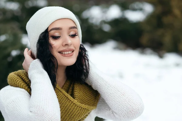 美しい女性の笑顔が通りの外に立つ雪の古い公園の森の天気冬の休日新年クリスマスは暖かいセーターやスカーフを編んだ服を着て 青い目のコピースペースぼやけたボケの背景 — ストック写真