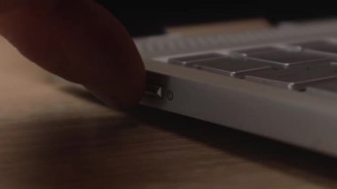 Erkek erkek, dizüstü bilgisayarın güç düğmesine basar. Dijital bilgisayar çalışmaya hazır. İşle meşgul çalışan programcı yönetici hazırlama aygıtı.