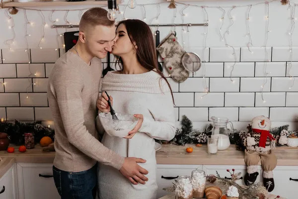 浪漫的年轻夫妇站在厨房亲吻拥抱做饭为家庭温馨的室内空气新年装饰圣诞假期派对庆祝概念冬夜 — 图库照片