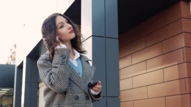 Sokakta dikilen güzel bir kadın kablosuz kulaklık takıyor müzik dinliyor ve tek başına eğleniyor. Bayan, mesai gününden sonra rahatlayın.