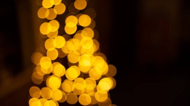 Kafe restoranının yakınındaki Bokeh arka plan efekti sokağında parıldayan soyut bir akşam. Şehir yaşamının odağından çıkarılmış altın renkli çelenkleri bulanıklaştırıyor. Yılbaşı partisi konsepti. 